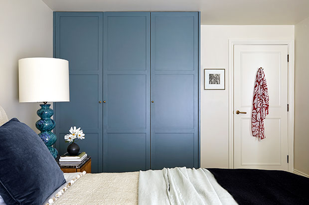 The principal bedroom contains a blue wardrobe set, and has matching blue accents such as the pillow, lamp, vases. The walls are white as are the comforters and lampshade. notting hill flat